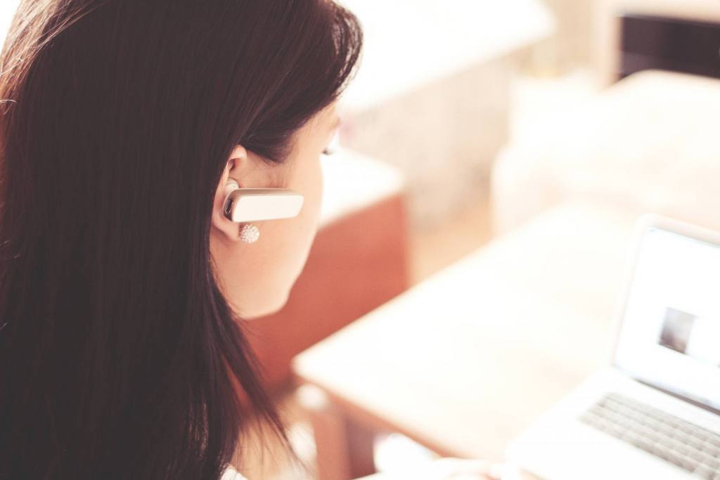 woman-wearing-earpiece-using-white-laptop-computer-210647